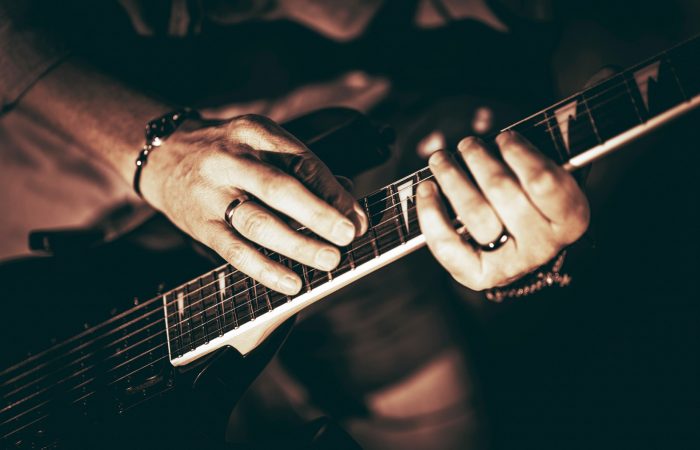 Rockman Playing Electric Guitar Closeup Photography. Hands on Guitar. Elegant Browny Color Grading.